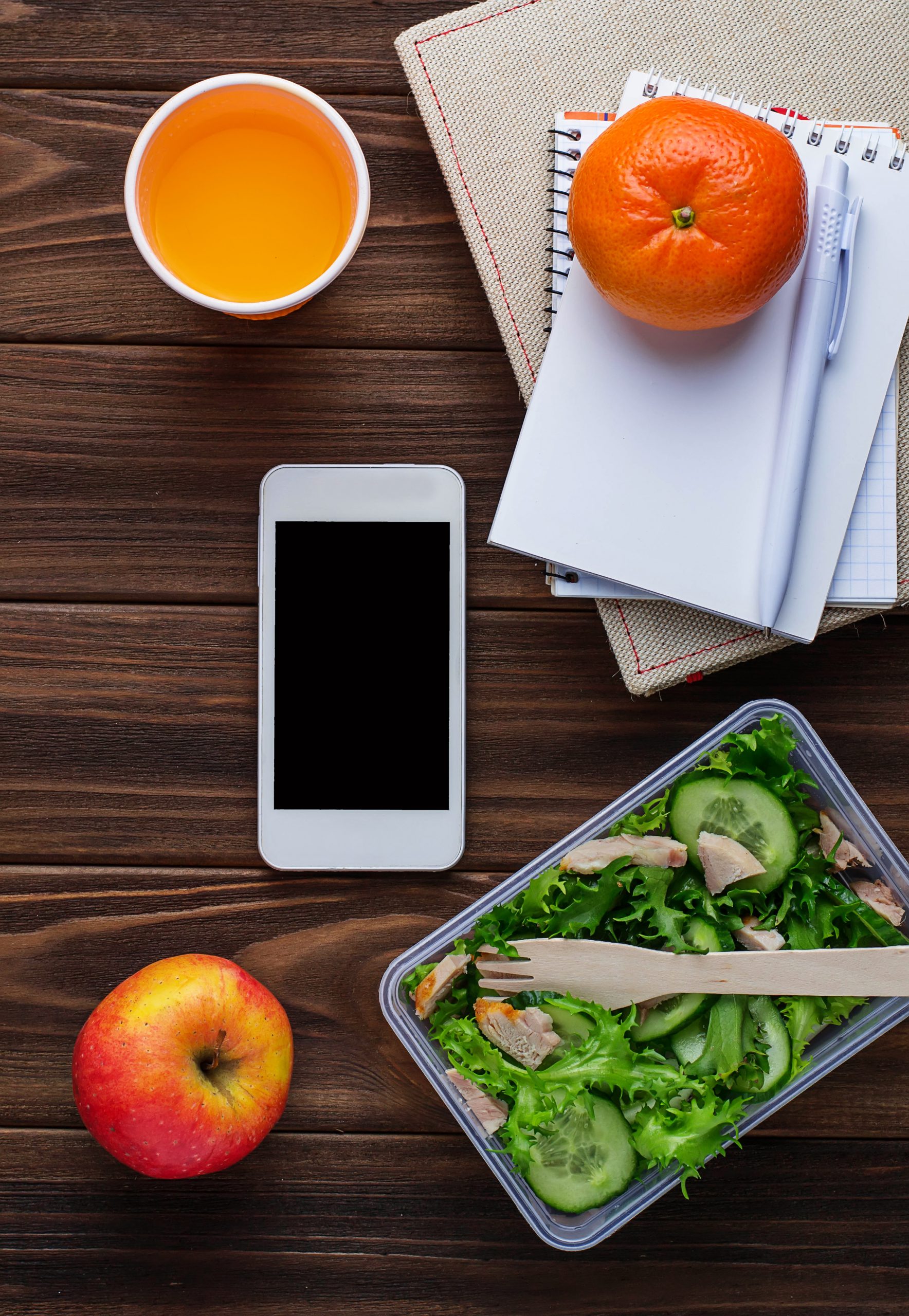 Lunch box with salad, notebook and phone